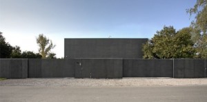 Безопасный монолитный коттедж с бетонной стеной как оградой